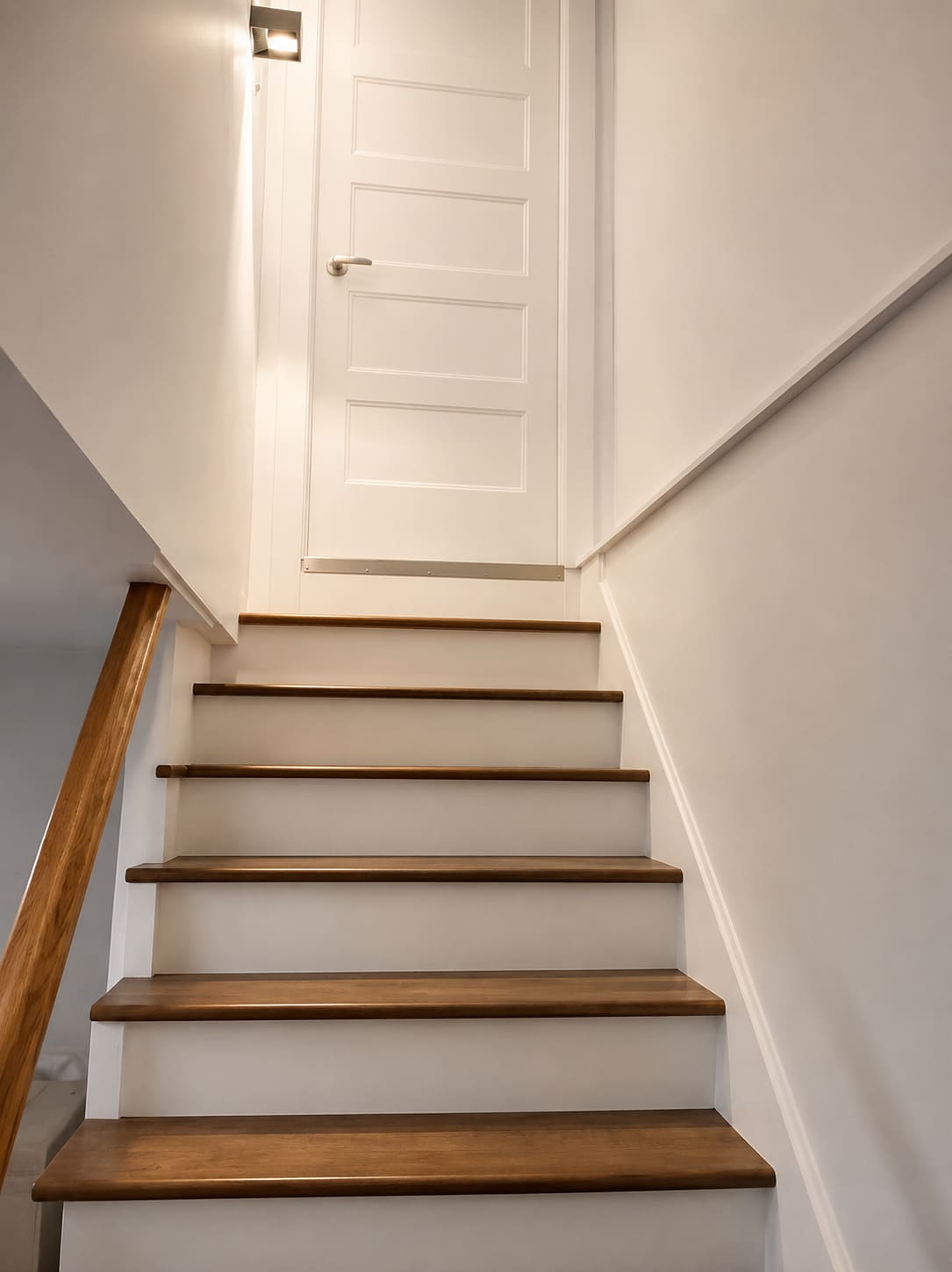 Escalier intérieur à contremarches blanches et rampe de bois